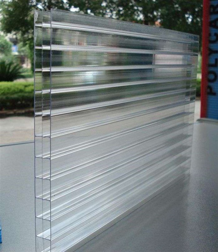 微信图片_20260216232904_173_14 - Clear corrugated plastic panel standing upright on a table outdoors, showing parallel ridges and a shiny translucent surface.