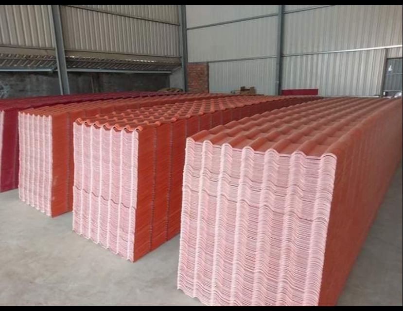微信图片_20260216232924_189_14 - Stacks of red corrugated metal roofing panels in a warehouse, neatly arranged on the concrete floor.