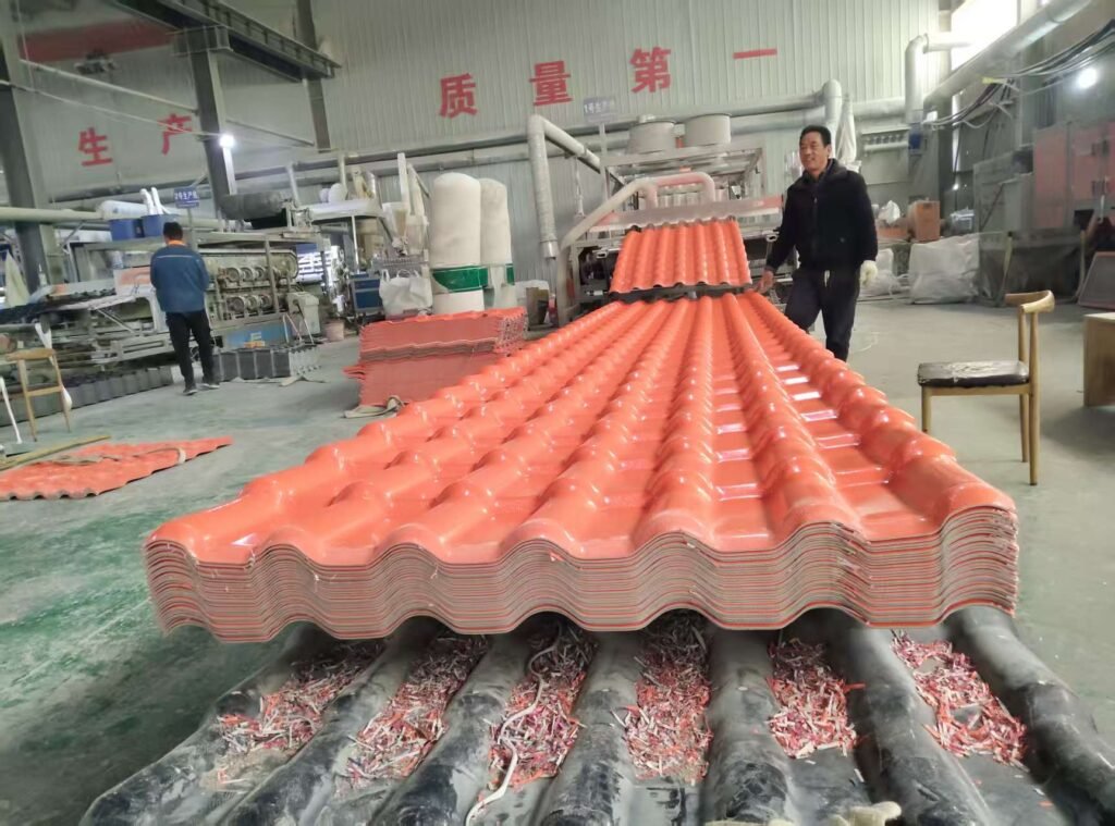 Factory interior with rows of red roof tiles stacked on a conveyor, two workers overseeing production.