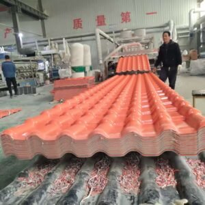微信图片_20260307135856_984_271 - Factory interior with rows of red roof tiles stacked on a conveyor, two workers overseeing production.