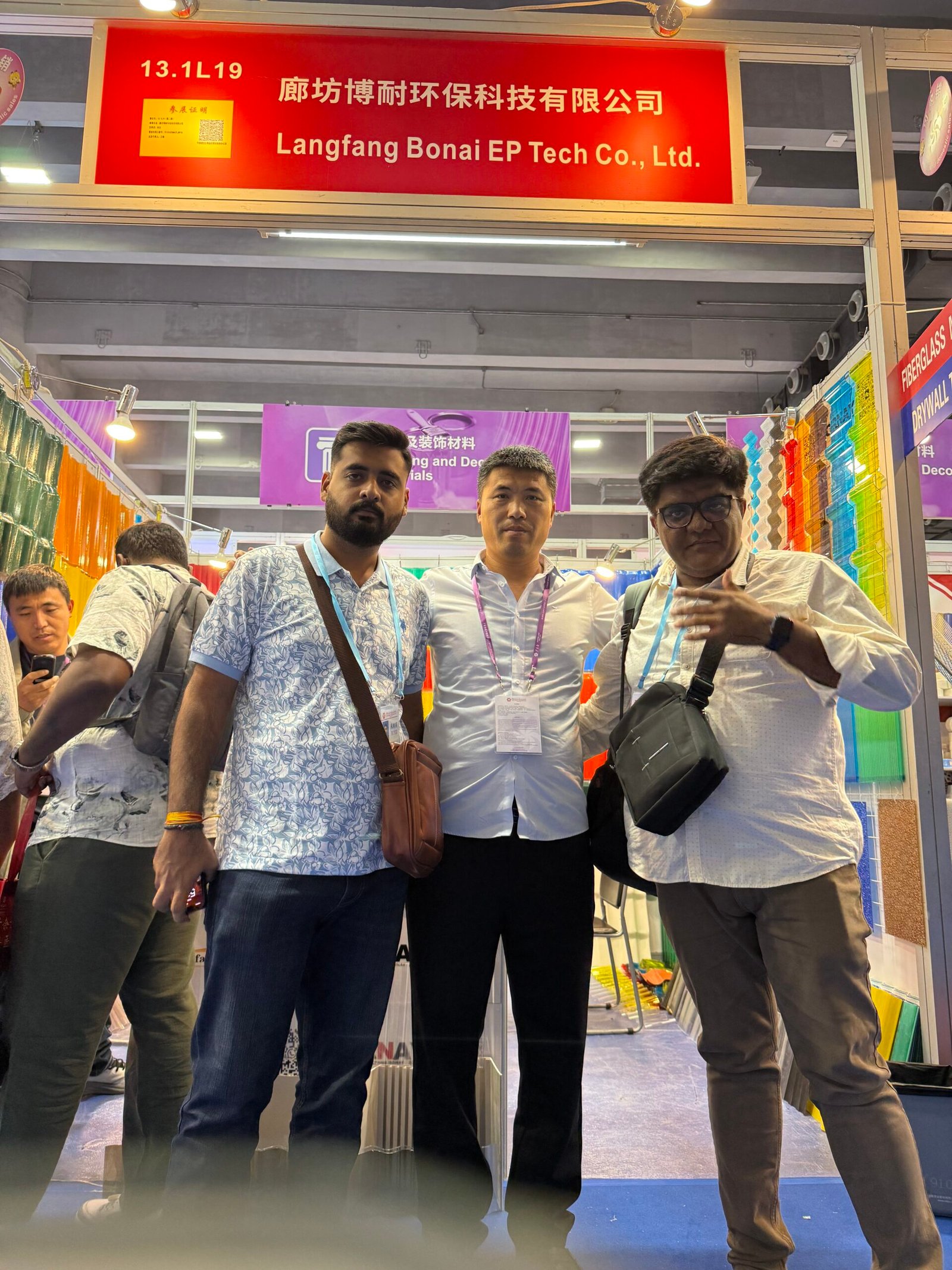 微信图片_20260330144021_419_14 - Three men posing at a trade show booth in front of a red company banner that reads Langfang Bonai EP Tech Co., Ltd.