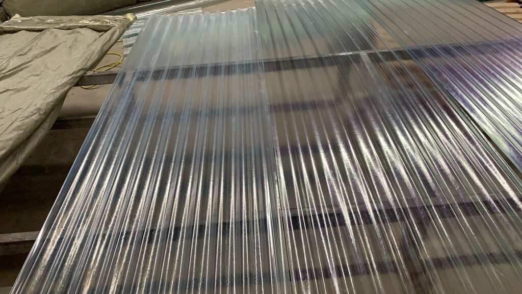 Corrugated galvanized steel roofing sheets stacked on a worktable in a workshop.