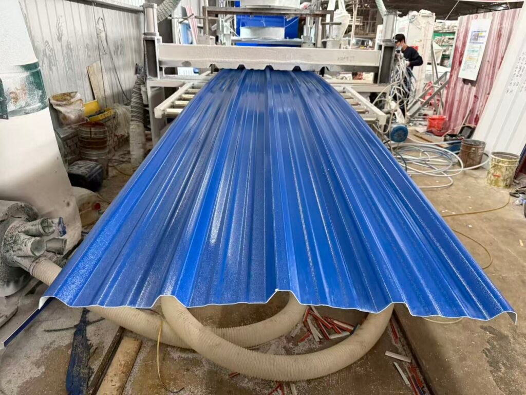 03ea3008594aeca2e8882eac24a19bb8 - Blue corrugated metal roof panel being formed on a rolling press in a workshop, with hoses, drums, and a worker in the background