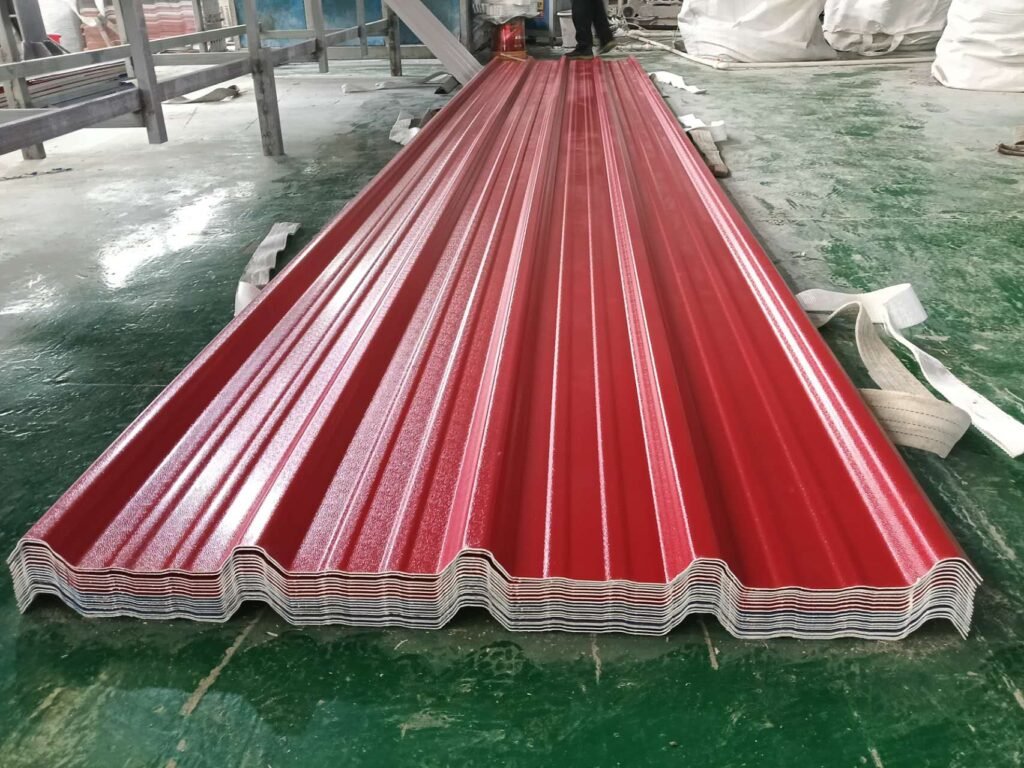 Stack of red corrugated metal roof panels laid on a green workshop floor, with white straps nearby.